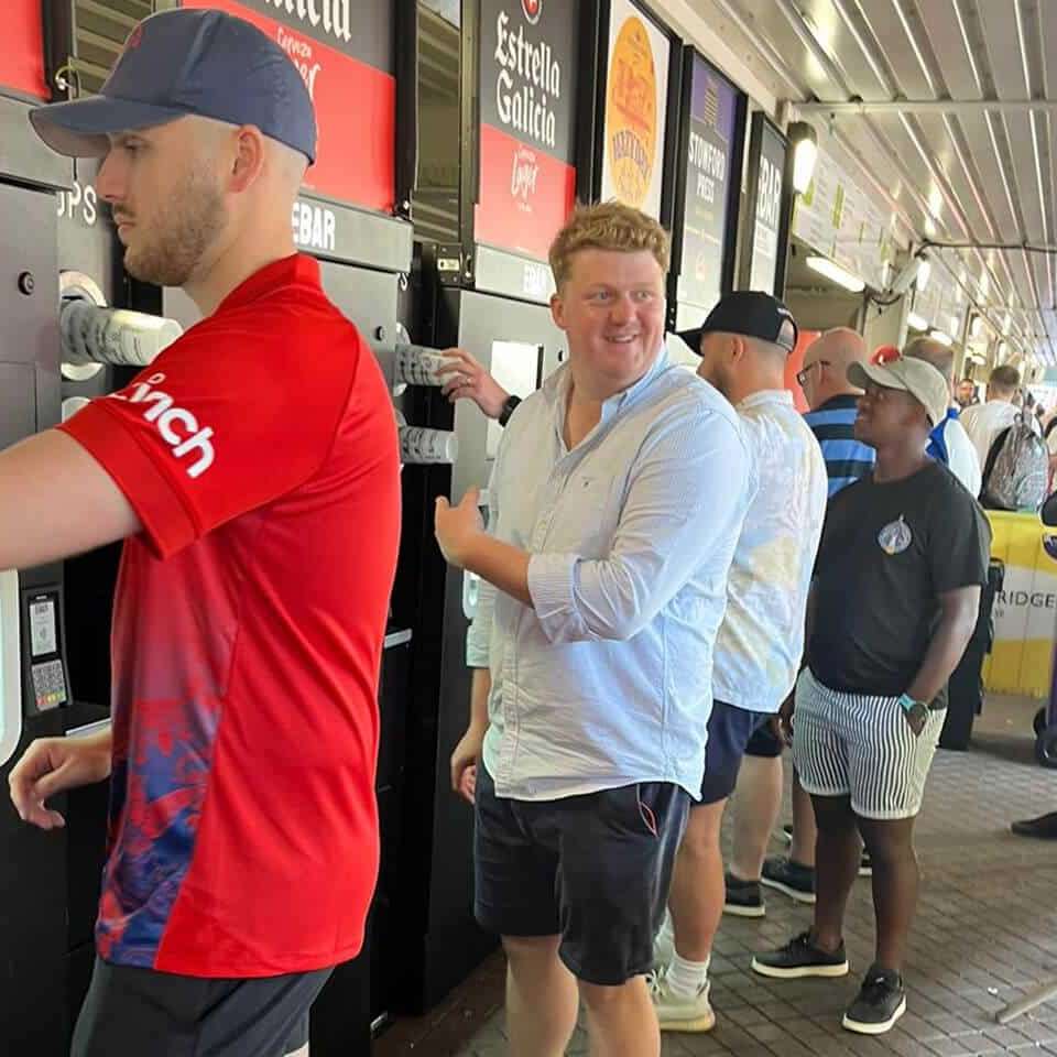 A man turns with a smile to point out something to a friend about the mobile EBar unit he is using