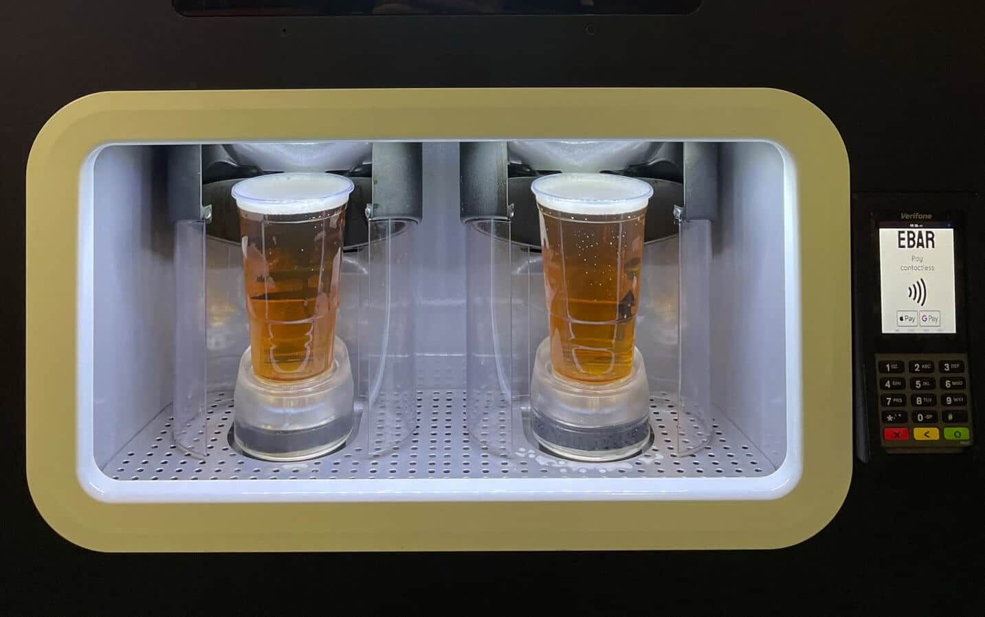 Two perfectly poured pints of lager in the pouring chamber of an EBar automated beer kiosk