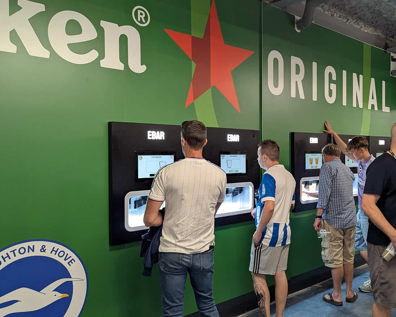 Football fans using a Heineken-branded 5-unit Beerwall at the Amex Stadium, Brighton and Hove Albion FC